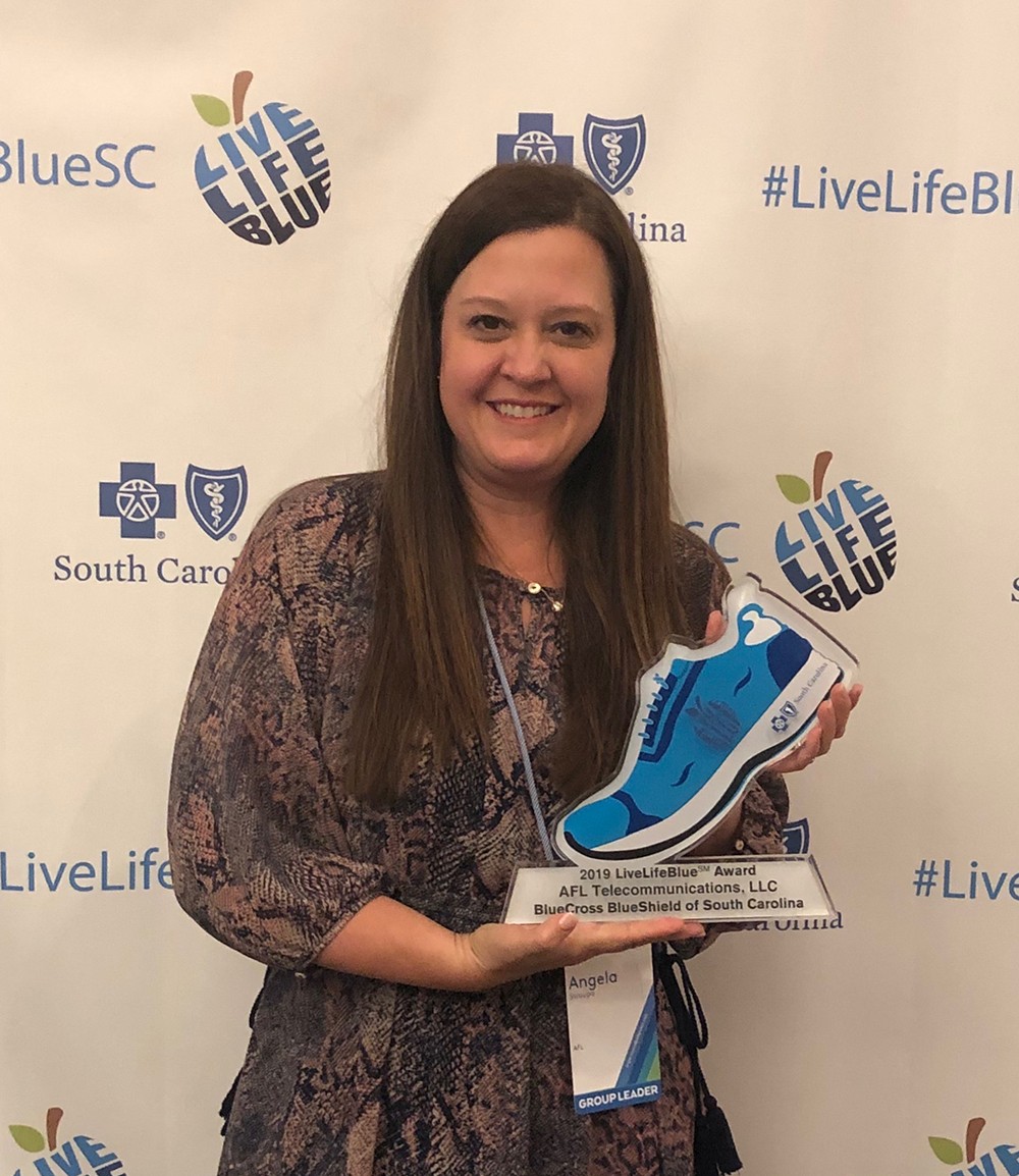 Angie Myers, benefits and wellness director for AFL, accepts the Blue Shoe award for the company. (Photo/Provided)
