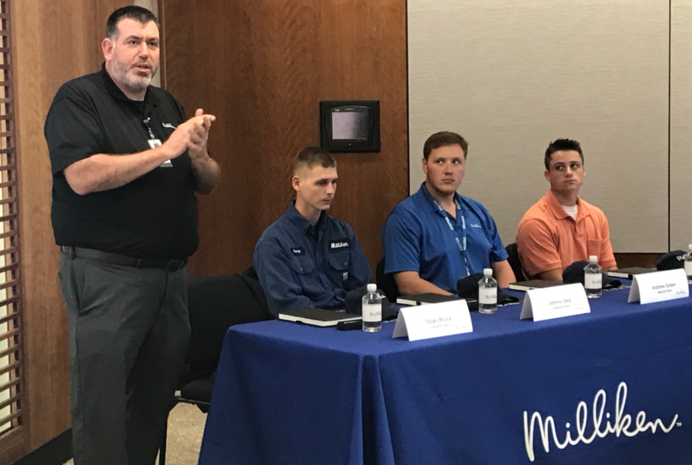 Kenny Parker, technical workforce manager at Milliken & Co., introduces the apprentices at a recent signing event. The students who signed apprenticeship commitments to Milliken & Co. were, from left, Johnny Deal, Andrew Green and Sam Mickel. (Photo/Teresa Cutlip)