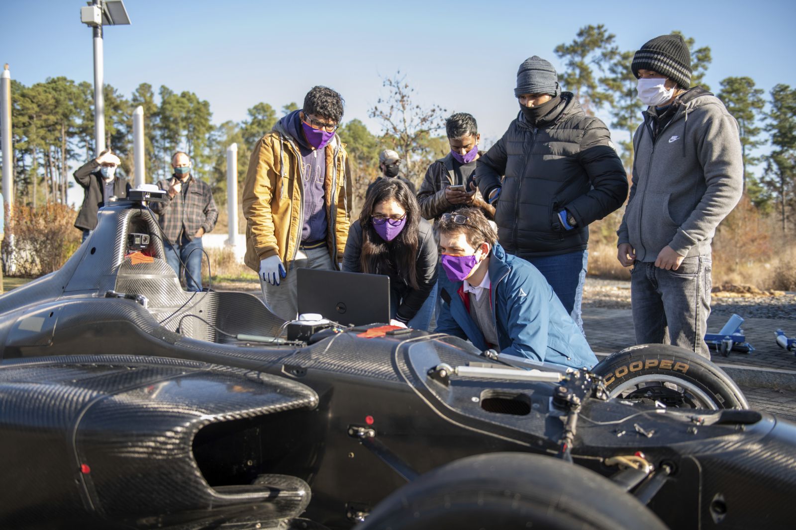 Members of the Deep Orange 12 team collaborate to test their new ride. In the background on the left stands a lightpole fitted with Poxyz's ultra-wideband receptor used to help navigate autonomous vehicles. (Photo/Provided)