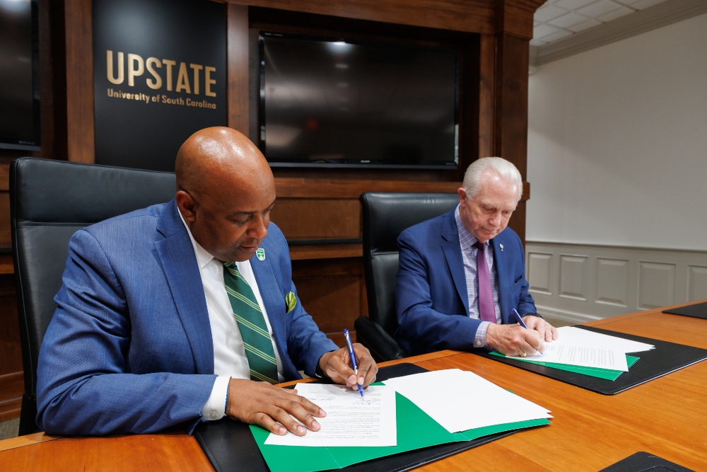 USC Upstate Chancellor Bennie L. Harris, left, and Greenville Technical College President Keith Miller sign the reverse transfer agreement. (Photo/Provided)